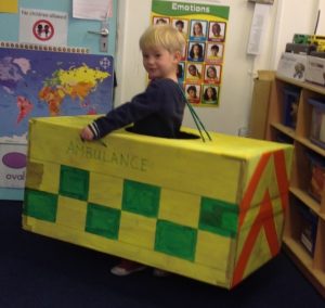 Small boy smiling inside a handmade cardboard ambulance